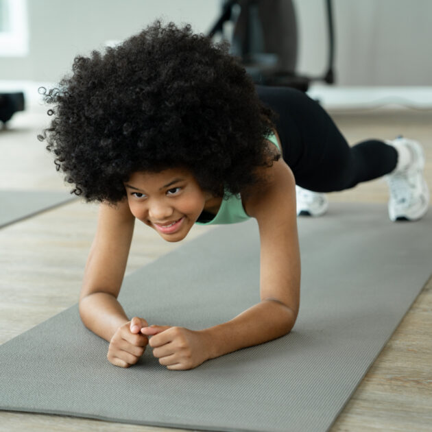 Portrait african american kid girl plank exercise at fitness gym