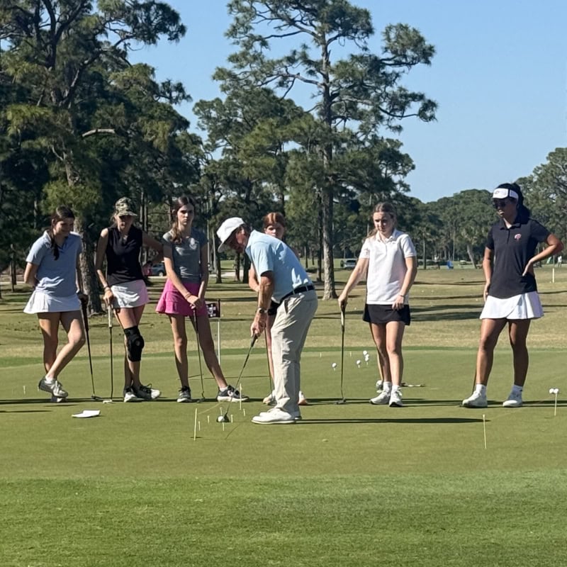 Man teaching girls to putt