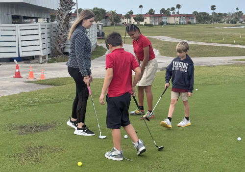 Young woman teaching children to golf
