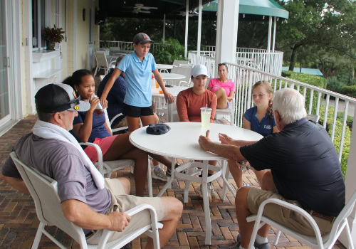 Man at table talking with youth golfers