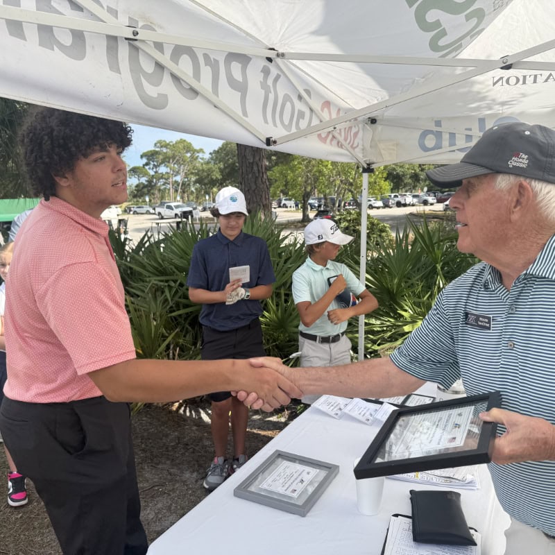 Man shaking young golfers hand